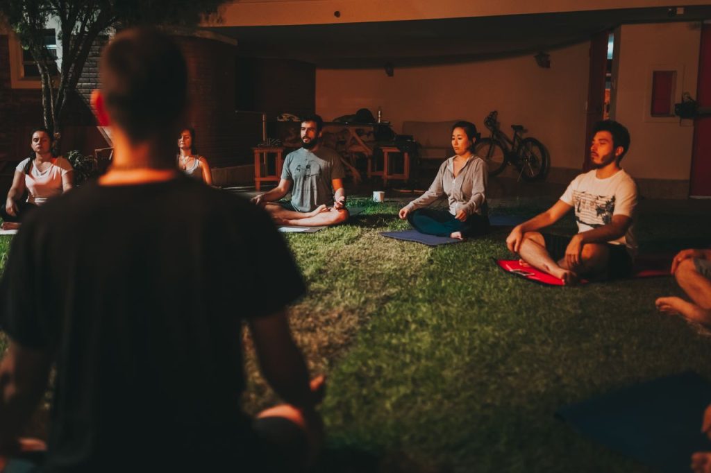 A diverse group of people meditating outdoors on a summer night.